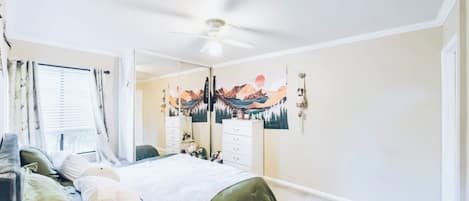 Ein Schlafzimmer mit Bett, Kommode, Spiegel und Deckenventilator.