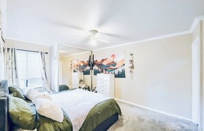 Ein Schlafzimmer mit Bett, Kommode, Spiegel und Deckenventilator.