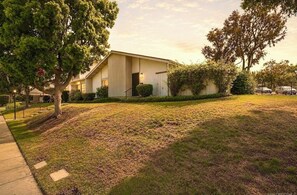 A building with a flat roof, a paved driveway, and a grassy area with trees. - Beautiful 2-bedroom townhome in delightful San Diego near the beach (San Diego)
