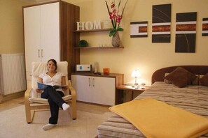 A room with a bed, a chair, a cabinet, and a wall with a 'HOME' sign and artwork. - House Renate for Singles (Schönau am Königssee)