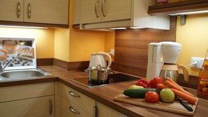 Eine Küche mit Holzausstattung, einer Kaffeemaschine, einem Wasserkocher und frischem Gemüse auf der Arbeitsplatte.