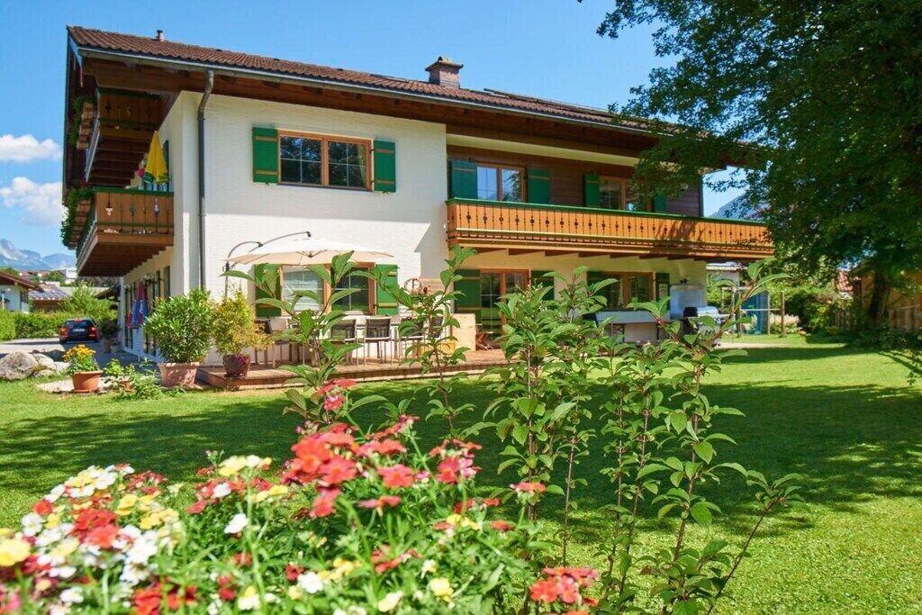 A two-story building with a balcony, a covered outdoor seating area, and a well-maintained garden with flowers.