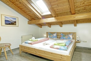 A bedroom with a wooden bed, a skylight, a radiator, and a chair. - Grünstein in the Thiele House (Schönau am Königssee)