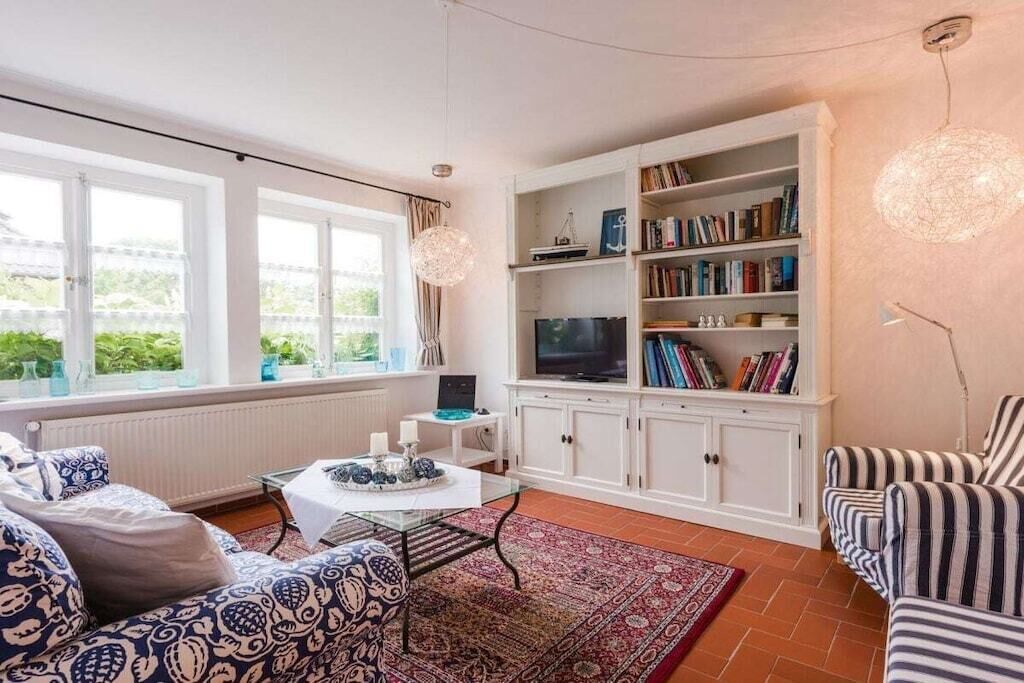 Ein Wohnzimmer mit einer Couch, einem Couchtisch, einem Bücherregal und einem Fernseher.