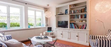 A living room with a sofa, a coffee table, a bookshelf, and a television.