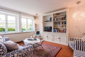 Ein Wohnzimmer mit einer Couch, einem Couchtisch, einem Bücherregal und einem Fernseher.