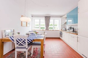 Cuina amb taula de menjador, cadires i finestra amb cortines.