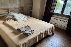 A neatly made bed with a beige bedspread, two pillows, and folded towels. - Holiday home with 3 bedrooms (Carpentras)