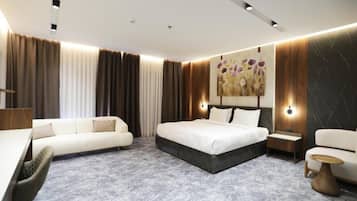 Een moderne hotelkamer met een groot bed, een bank, een bureau en een kleine tafel.