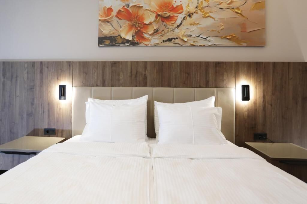Une chambre d’hôtel avec un grand lit, deux tables de chevet et une œuvre d’art accrochée au mur.