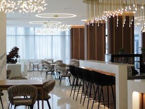 A modern interior with a bar area, seating, and a chandelier. - Hotel Gallery  (Gjilan)
