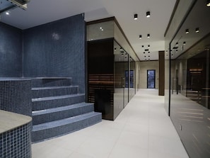 Un pasillo moderno de hotel con pared de azulejos, una escalera y un panel de vidrio.