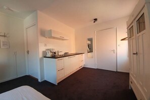 Ein Schlafzimmer mit einem Bett, einer Küchenzeile mit Schränken und einer Tür zu einem weiteren Raum.