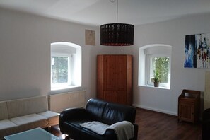 Un salon avec un canapé en cuir noir, un meuble en bois et un luminaire suspendu.