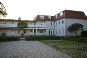 Ein Gebäude mit einem überdachten Innenhof, einem zentralen Eingang und einem kleinen Baum.