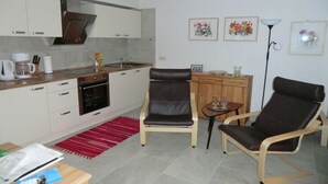 A compact living space with a kitchenette, a dining area with two chairs, a small table, and a red rug. - Holiday apartment with 1 bedroom (Potsdam)