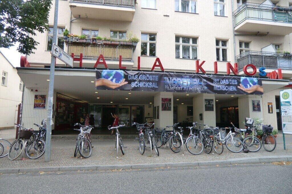 En bygning med et skilt, der siger 'HALIA KINO', og flere cykler parkeret foran.