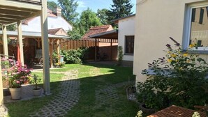 A covered patio area with a wooden table and chairs, a bicycle, and potted plants. - Holiday apartment with 1 bedroom (Potsdam)