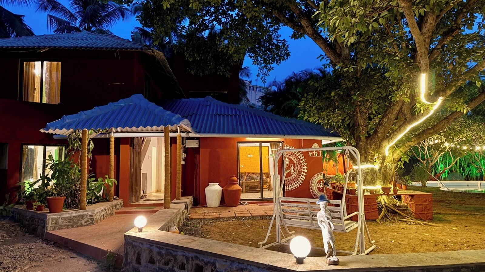 Een huis met een overdekte veranda, een schommel en een kleine tuin.