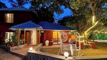 Een huis met een overdekte veranda, een schommel en een kleine tuin.