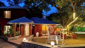 Een huis met een overdekte veranda, een schommel en een kleine tuin.
