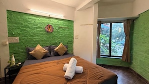 Een slaapkamer met een groen gestructureerde muur, een bed met bruin beddengoed en een raam met gordijnen.
