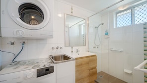 A modern bathroom with a built-in washing machine, a sink, and a shower area. - Star Lodge unit 6 Bulcock Beach QLD (Caloundra)