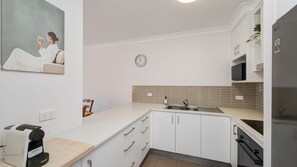 A modern kitchen with white cabinets, a built-in oven, and a sink. - Star Lodge unit 6 Bulcock Beach QLD (Caloundra)