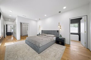 Ein modernes Schlafzimmer mit einem großen Bett, Nachttischen, einem Kleiderschrank und Balkonblick.
