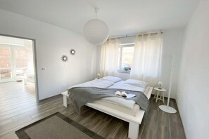 Ein modernes Schlafzimmer mit einem Bett, Nachttischen, einer Stehlampe und einem Fenster mit Vorhängen.