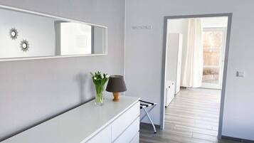 Ein modernes Badezimmer mit einem weißen Waschtisch, einem Spiegel und einer Vase mit Blumen.