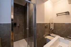 Un baño moderno con ducha de vidrio, un lavabo blanco y un perchero para toallas.