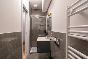 Ein modernes Badezimmer mit Duschkabine aus Glas, einem Waschbecken und einem Handtuchhalter.