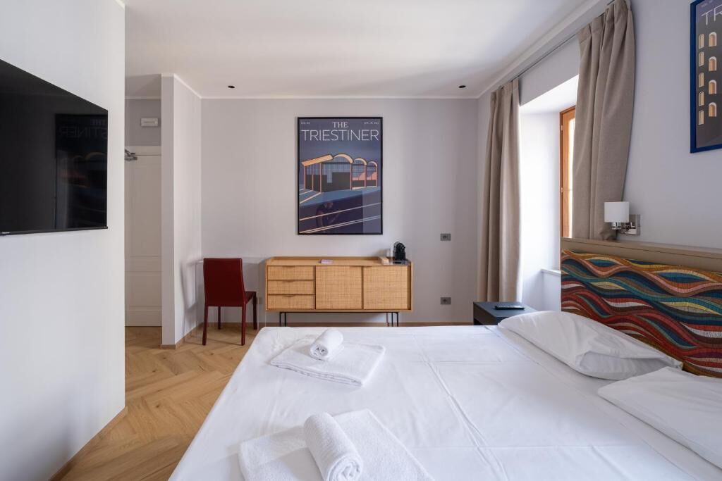 Une chambre d’hôtel avec un lit, un bureau, une chaise, une télévision et une affiche au mur.