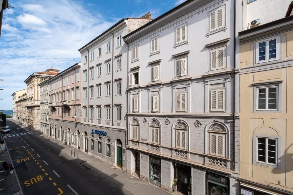 Una vista di strada con una fila di edifici, cielo sereno e corsia riservata agli autobus.
