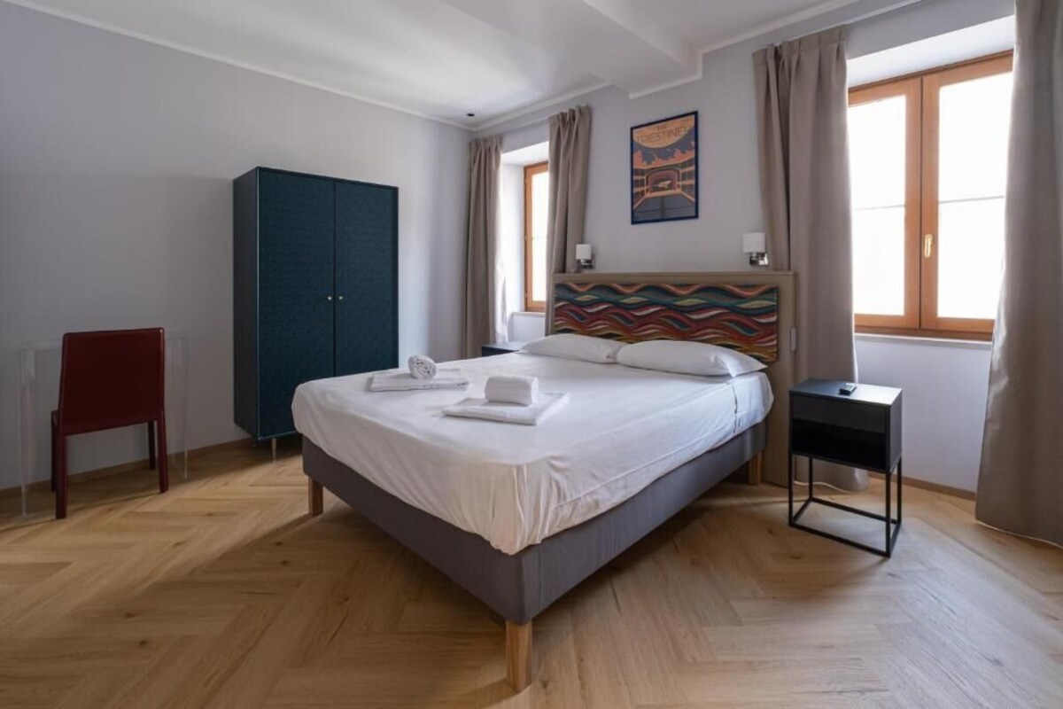 Un dormitorio con cama, armario, silla y mesita de noche.