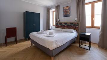 Una camera da letto con un letto, un armadio, una sedia e un comodino.