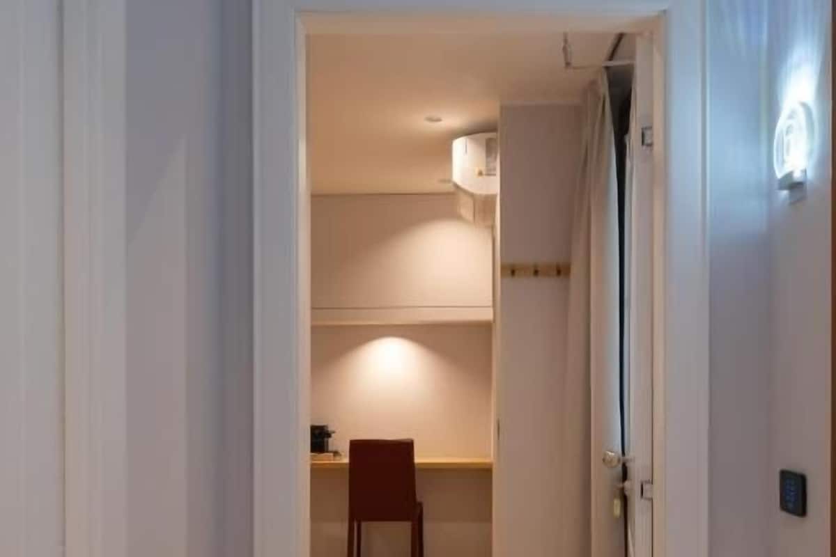 Un pasillo que conduce a una habitación con piso de madera y una silla.