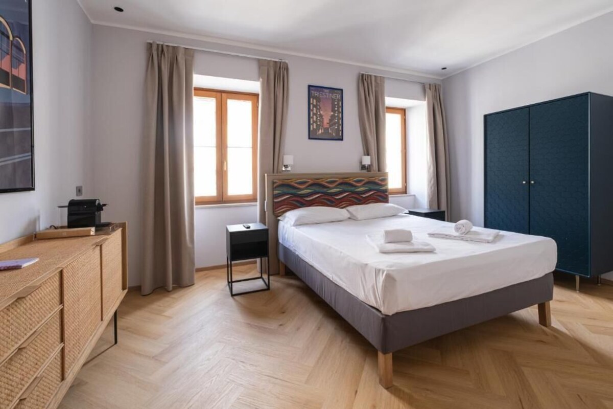 Ein Hotelzimmer mit Bett, Kleiderschrank, Schreibtisch und einem fenster mit Vorhängen.