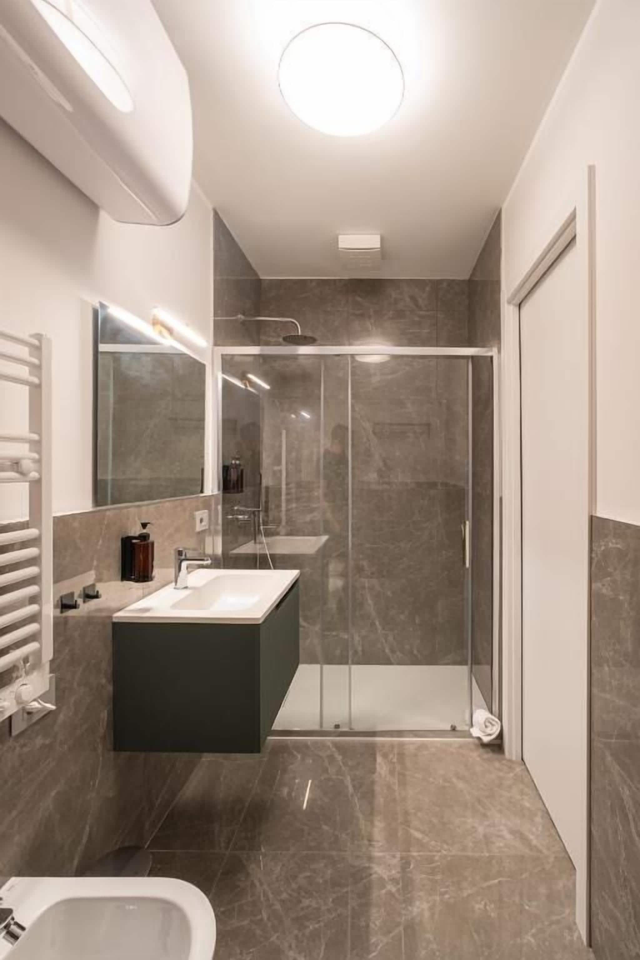 Une salle de bain moderne avec une douche à parois de verre, un lavabo intégré et des toilettes.
