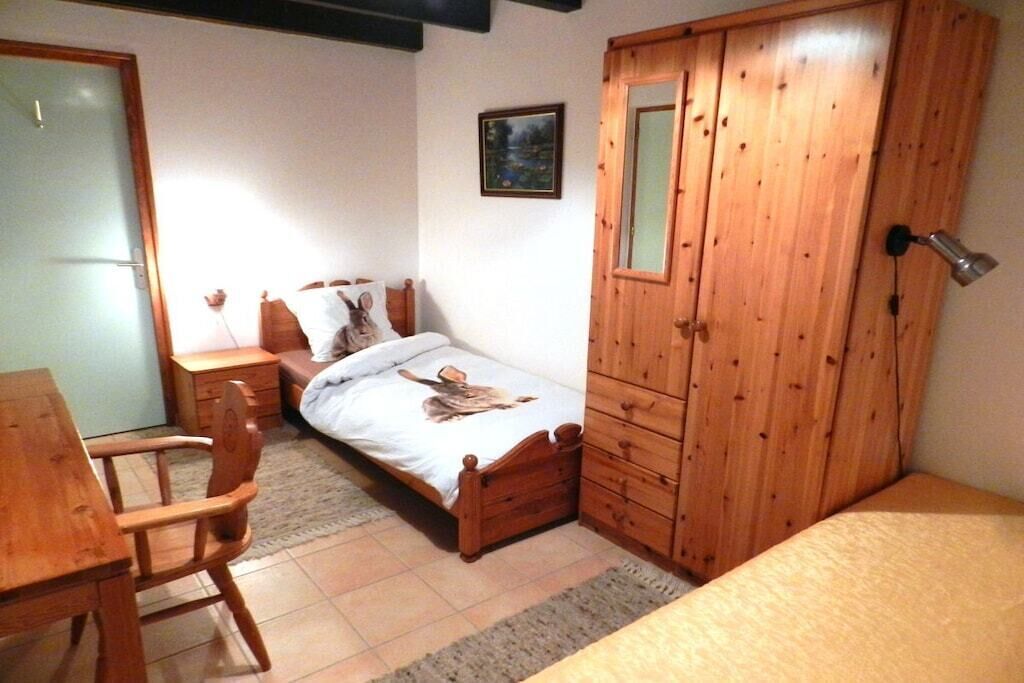 A bedroom with a wooden bed, a wooden wardrobe, a wooden desk, and a chair.