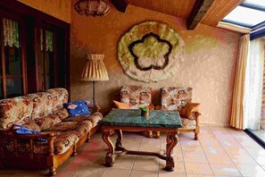 A room with a sofa set, a table, and a patterned wall hanging. - Domaine du Val des Ragondins (Sainte Croix)