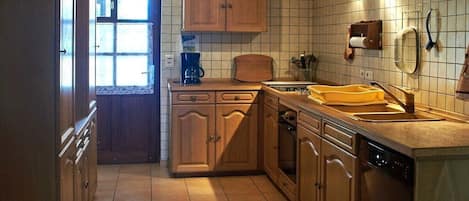 A kitchen with wooden cabinets, a dishwasher, and a window with blinds.
