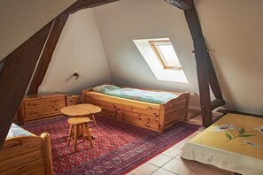 A small attic bedroom with a sloped ceiling, a single bed, a small table, a stool, and a window. - Domaine du Val des Ragondins (Sainte Croix)