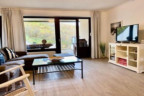 Een woonkamer met een bank, salontafel, televisie en een boekenkast.