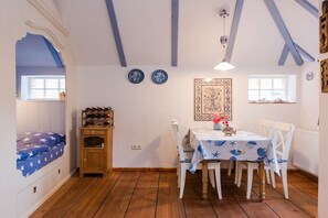 Quarto com cama, mesa de jantar, cadeiras, armário de madeira e um painel de parede estampado.
