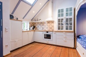 A compact kitchen with white cabinets, a wooden countertop, and a built-in oven. - Holiday home with 2 bedrooms (Greetsiel)