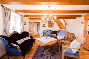 Una habitació acollidora amb un sofà blau fosc, una taula de dinar de fusta amb cambrera de puntes i un penjallum.