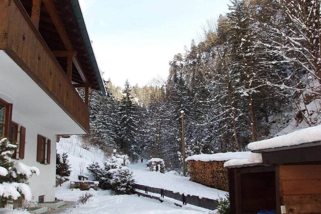 Ein hölzernes Gebäude mit verschneiter Fassade, umgeben von schneebedeckten Bäumen und einem klaren Himmel.