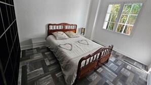 Una camera da letto con un letto in legno, una finestra vista su del verde e un pavimento decorato.